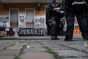 «Syndikat bleibt» steht an einer Fassade. Polizisten vor der Kiezkneipe Syndikat