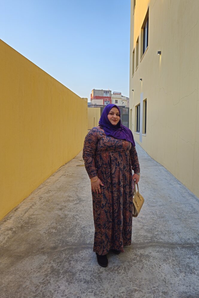 Eine Frau mit Schleier und langem Kleid steht in einer kleinen Gasse