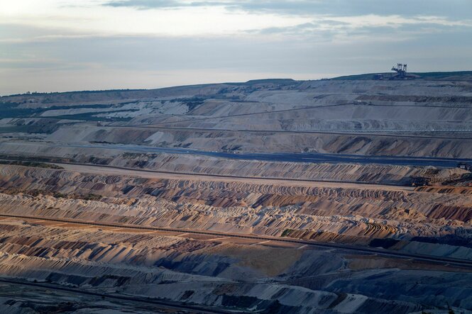 Abraum-Erdwall um Abraum-Erdwall und in der Ferne fördert ein Bagger im Tagebau Hambach Braunkohle