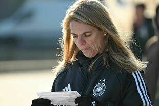 Nia Künzer schaut in DFB-Jacke auf einen Zettel