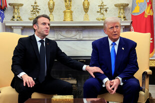 Emmanuel Macron hält Donald Trumps Arm fest und berichtigt ihn im Oval Office sitzend