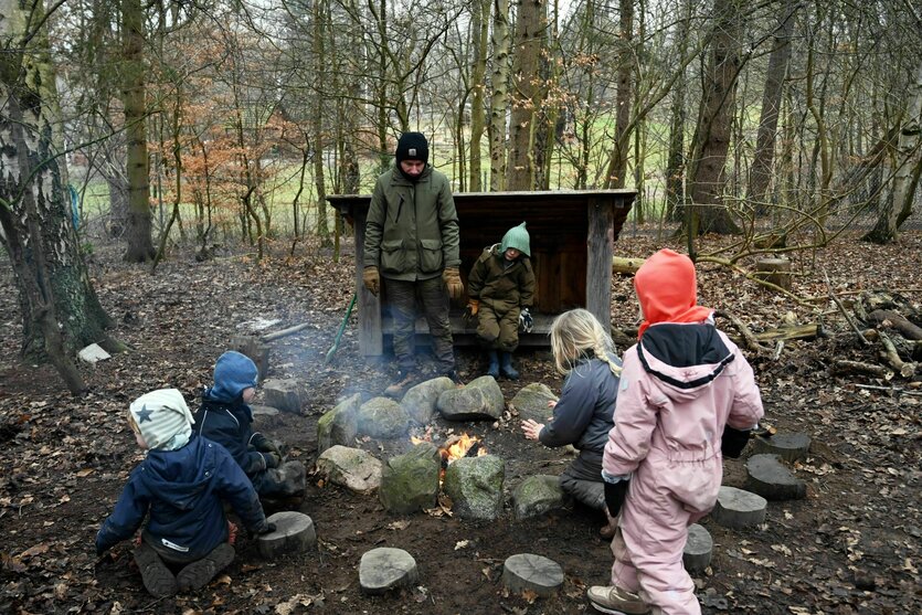 Kinder spielen im Wald am Lagerfeuer