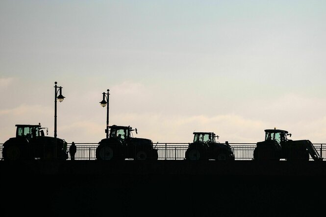 Silhouette von Treckern auf einer Brücke