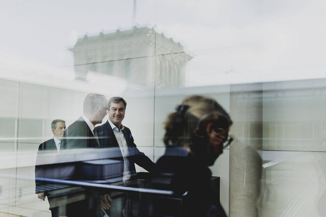 Friedrich Merz und Markus Söder sind durch eine Glasscheibe fotografiert