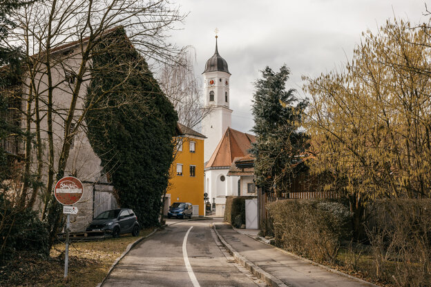 Eine Straßenszene in einem Dorf mit einer Kirche im Hintergrund