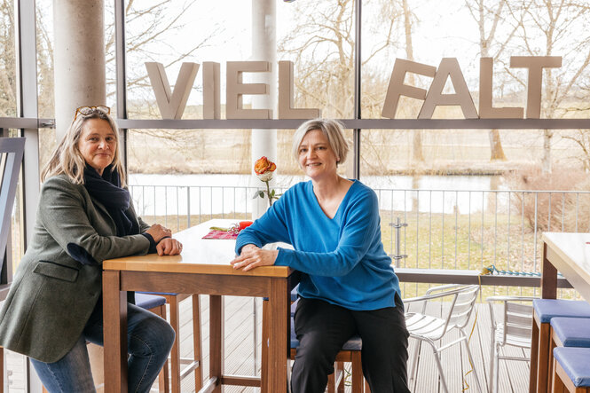 In einem Café lehen sich zwei Frauen an einen Stehtisch