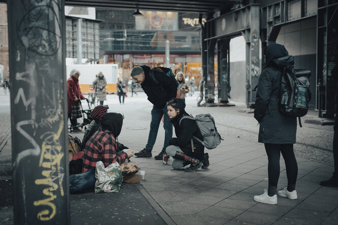 Sozialarbeiter betreuen einen obdachlosen Menschen unter einer Brücke beim Alexanderplatz