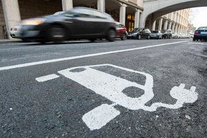 Ein Symbol für ein Elektroauto markiert einen Parkplatz neben einer E-Ladesäule.