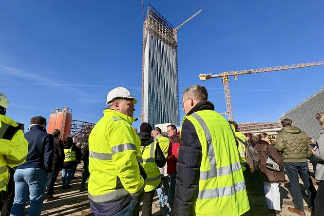 Männer in Warnwesten, im Hintergrund ein Hochhaus