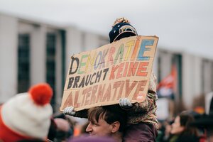 Zu sehen ist ein Kind auf den Schultern einer erwachsenen Person. Es hält ein Schild mit der Aufschrift: Demokratie braucht keine Alternative,