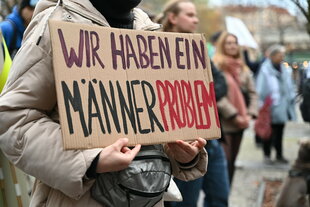 Eine Frau hält ein Schild mit der Aufschrift "Wir haben ein Männerproblem" während einer Demonstration am Internationalen Tag für die Beseitigung von Gewalt gegen Frauen.