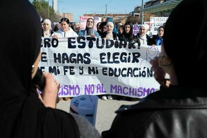 Junge Frauen mit Kopftuch tragen ein Transparent auf einer Demonstration. auf dem Transparent steht: 