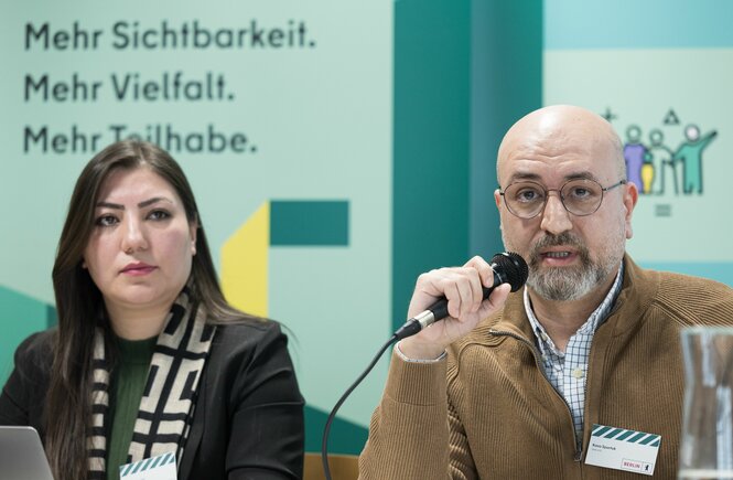 Eine Frau und ein Mann sitzen auf einem Podium