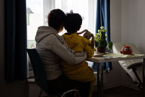 Eine Frau und ein Kind sitzen an einem Tisch und schauen aus dem Fenster