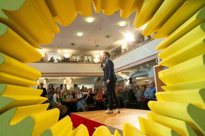 Felix Banaszak steht auf einer bühne bei einer Veranstaltung.