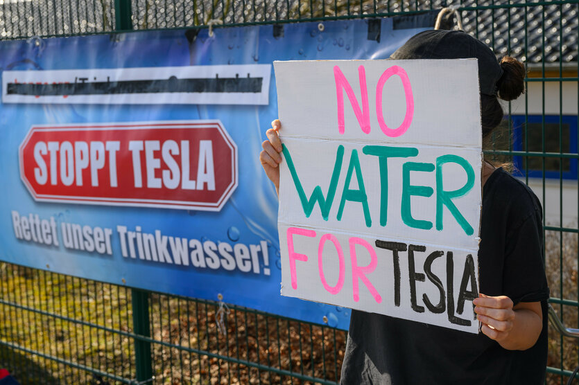 Teilnehmer einer Protestaktion vor der Sitzung des Wasserverbandes Strausberg-Erkner (WSE) halten Schilder mit der Aufschrift "No Water for Tesla"