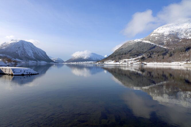 Schneebedeckte Berge spiegeln sich im Fjord