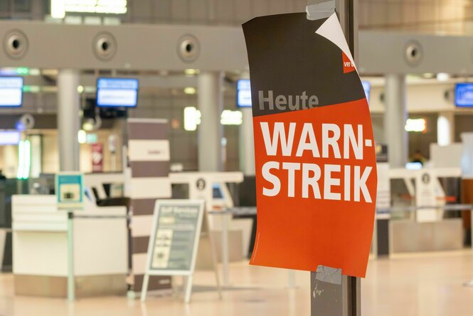 Ein Plakat mit der Aufschrift "Warnstreik" in einem leeren Flughafen