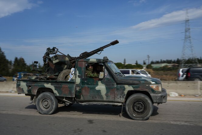 Kämpfer transportieren mit einem Pick-up in militärischer Tarnfarbe eine Kanone