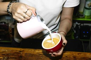 Ein Barista gießt gekonnt Milch in den Espresso