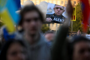 Demonstrierende in der Slowakei mit ukrainischer Flagge und einem Bild des Ministerpräsidenten Fico mit der Aufschrift "Agent"