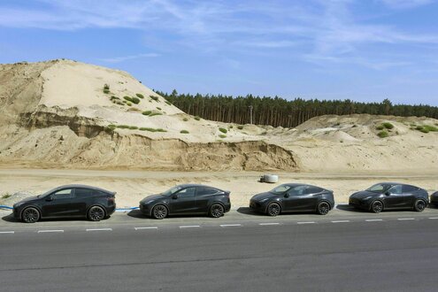 Y-Modelle stehen vor Sandbergen im Hintergrund auf dem Tesla-Werksgelände in Grünheide