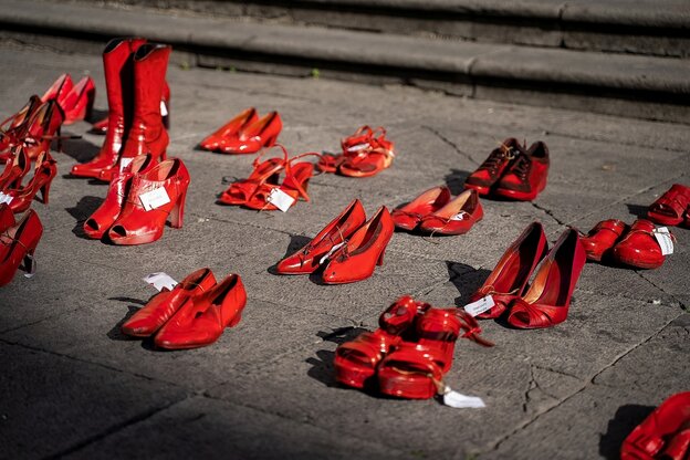 Mehrere Paare roter Schuhe stehen auf dem Asphalt