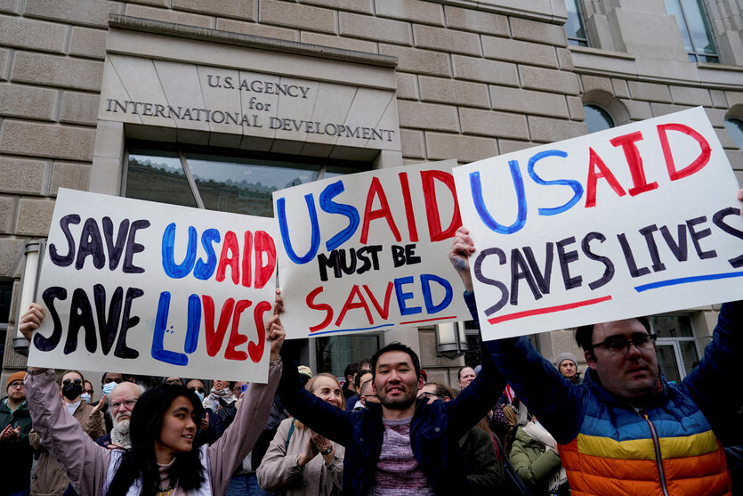 Demonstrantinnen halten Schilder hoch, auf denen auf englisch steht: USAID rettet leben