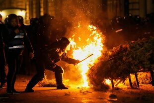 Die Polizei versucht, ein Feuer zu löschen, während Anhänger von Calin Georgescu protestieren, nachdem die rumänische Wahlbehörde seine Kandidatur bei der Wiederholung der Präsidentschaftswahlen in Bukarest, Rumänien, abgelehnt hat