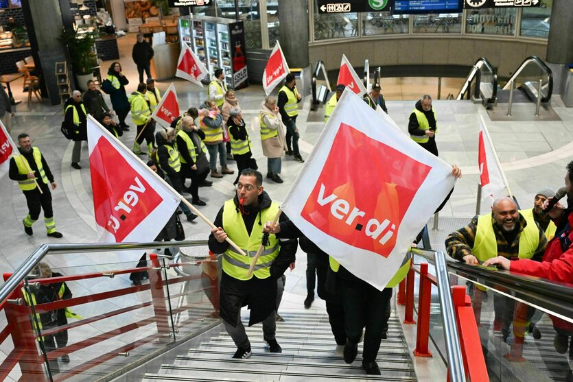 Mitglieder der Gewerkschaft Verdi gehen mit Fahnen bei einem Streik durch ein Teminal des Stuttgarter Flughafens