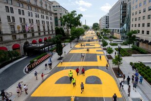 Große gelbe Buchstaben beginnen das Wort "Black" auf einem langen Boulevard