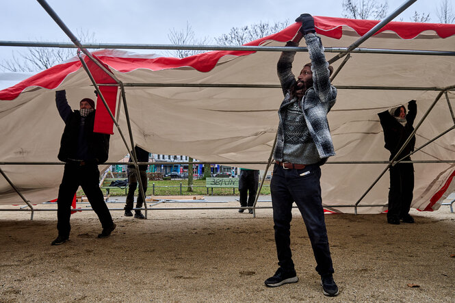 Männer spannen eine Plane über ein Gerüst: Das Protestcamp am Oranienplatz in Kreuzberg wird aufgebaut