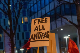 Ein Schild mit dem Spruch "Free All Antifas" auf einer Demo anlässlich eines erneuten Prozessbeginns im Rondenbarg-Verfahren in Hamburg am 20. 01. 2024.