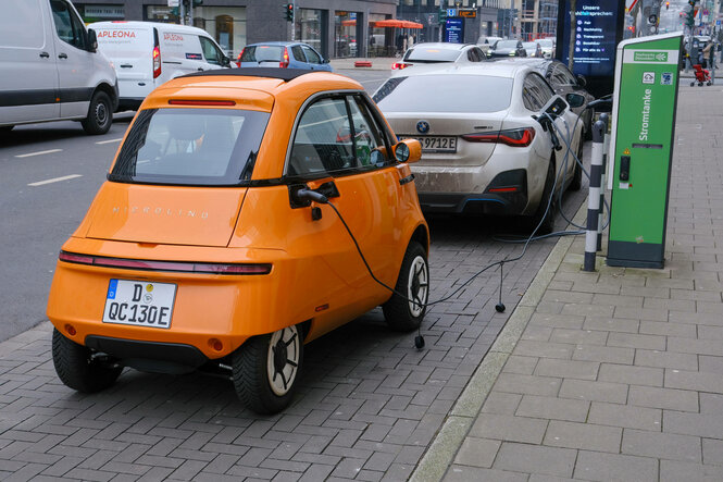 Ein oranges E-Auto steht an einer Ladestation