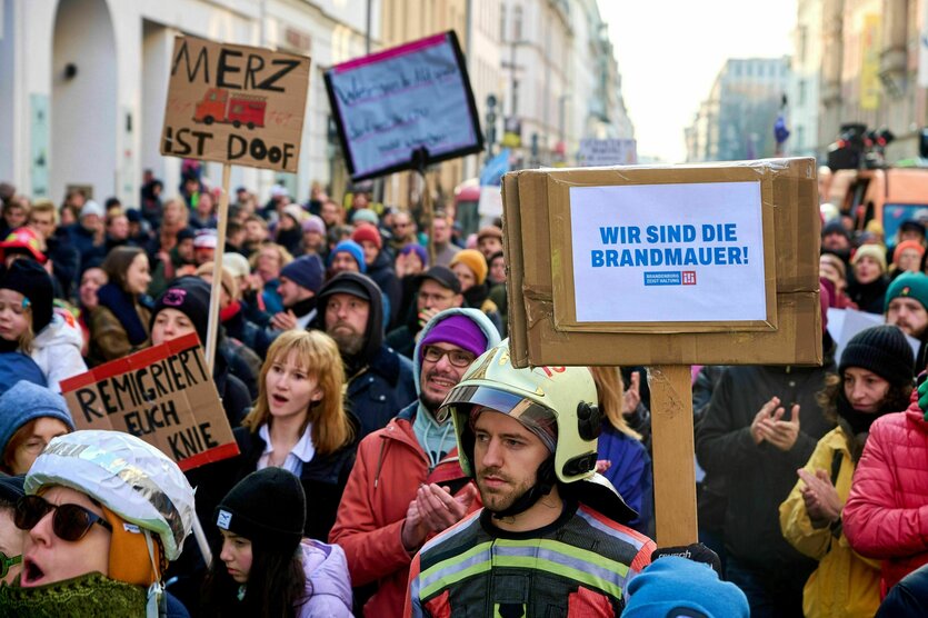 Protestaktion auf der Straße - die Protestierenden halten Schilder hoch "wir sind die Brandmauer" und "Merz ist doof"