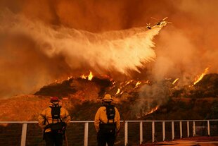 Feuerwehrleute beobachten, wie Löschwasser auf das Palisades-Feuer im Mandeville Canyon Angeles geworfen wird