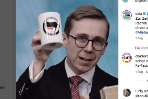 Ein Mann im Anzug hält eine Tasse hoch