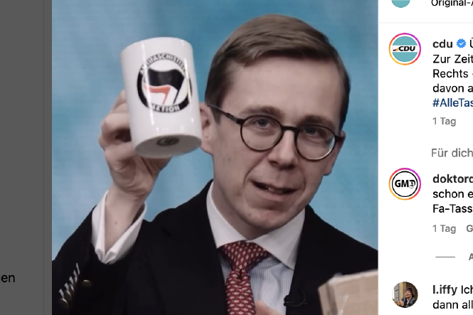 Ein Mann im Anzug hält eine Tasse hoch