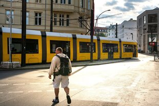 Ein Mann läuft in Berlin auf eine einfahrende Tram zu.