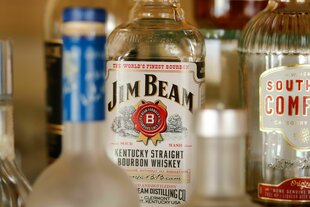 Eine Flasche Jim Beam Kentucky Bourbon Whiskey steht zwischen weiteren alkoholischen Getränken auf der Bar in einem Hotel