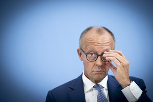 Ein Mann im Anzug fasst an seine Brille