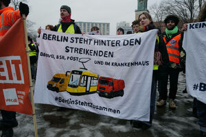 Menschen bei eine Kundgebung halten Banner mit der Aufschrift. 