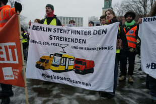 Menschen bei eine Kundgebung halten Banner mit der Aufschrift. "Berlin steht hinter den Sttreikenden"