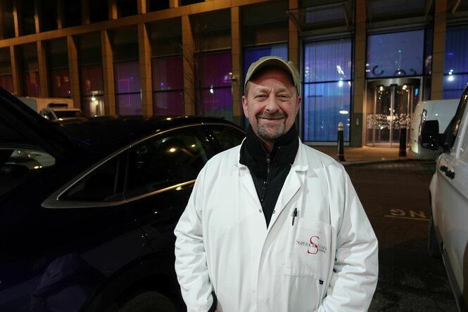 Craig Atkins,ein Händler, steht in weißem Kittel vor der Markthalle