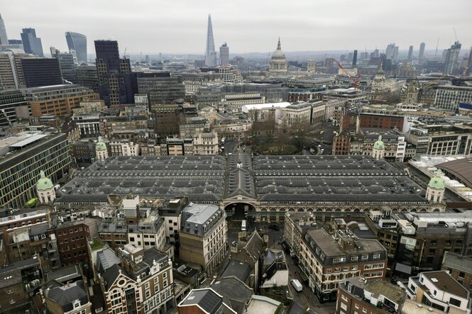 Luftbildaufnahme ziegt das dicht bebaute historische Viertel, in der Mitte der Fleischmarkt mit seiner viktorianischen Fassade, im Hintergrund die Skyline von London