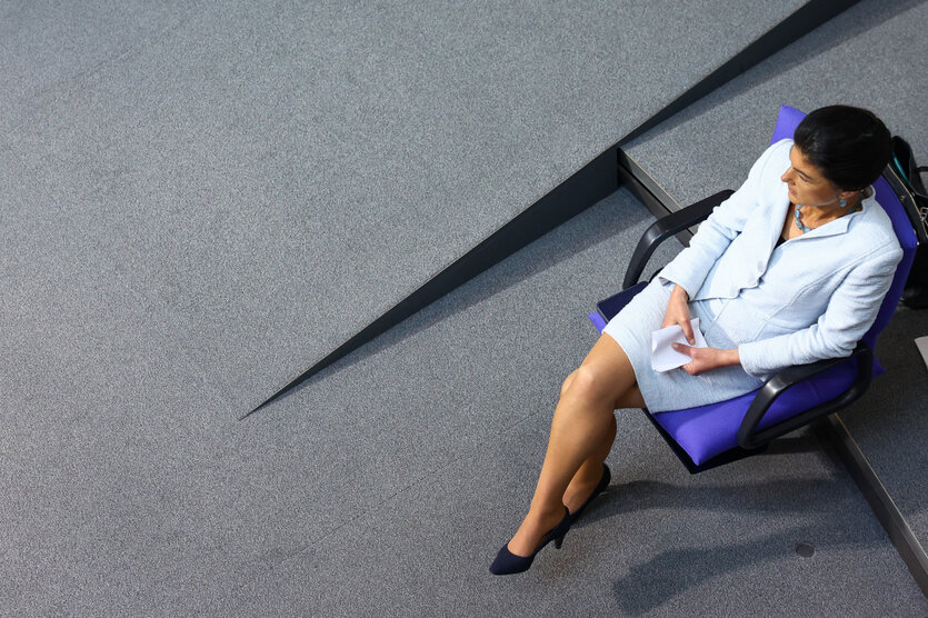 Eine Frau sitzt mit einem weißen Kleid auf einem lila Stuhl