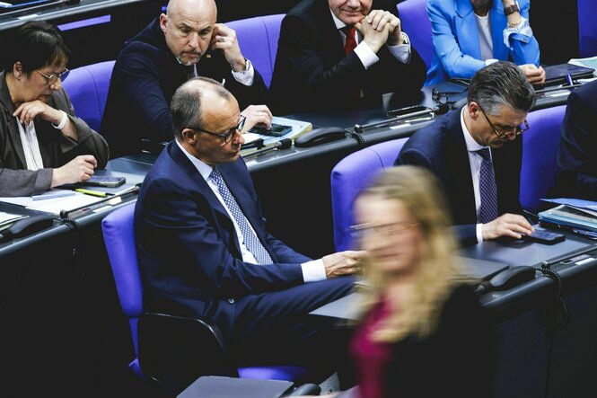 Bundestag, Friedrich Merz sitzt mit seinen Parteifreunden am Platz, während Katharina Dröge vorbei geht. Sie ist in der Unschärfe