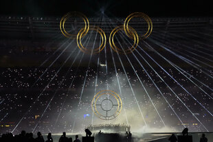 Im dunklen Olympiastadion von Paris wird ein beleuchteter Ring zu den vier anderen Ringen nach oben gezogen