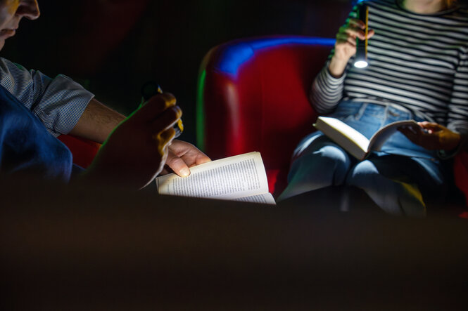 Lesende mit Taschenlampen und hell erleuchtete Buchseiten