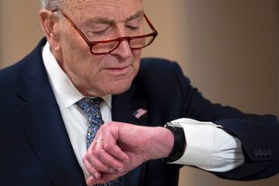 Chuck Schumer schaut auf seine Uhr am Armgelenk